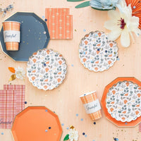 Confetti flat lay with plaid cups and patterned plates arranged for a fall party.