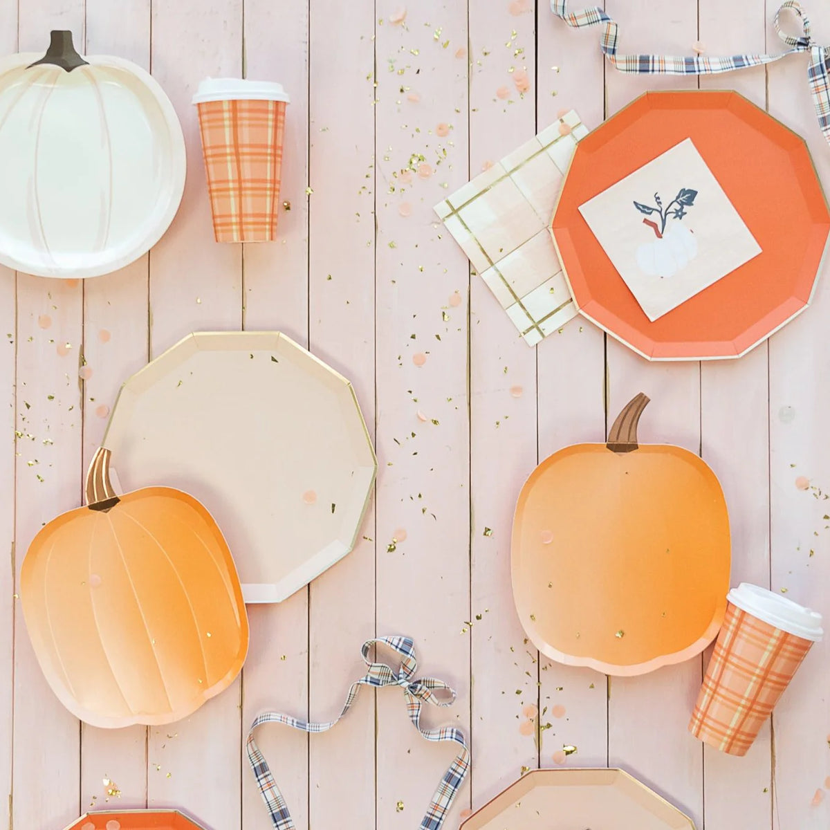 Flat lay of pumpkin-shaped plates, octagon plates, plaid cup, and napkins.