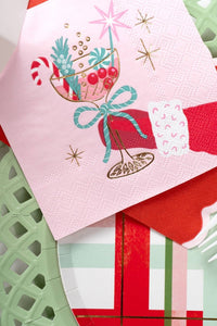 Close-up angled view of the pink retro Christmas cocktail napkin resting directly on a solid red scalloped paper napkin.