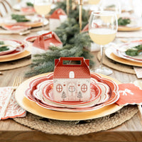 Close-up of the scalloped charger plates and matching layered plates with a small cottage treat box on a holiday table.