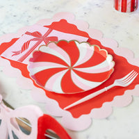 Detailed view of the scalloped party plates placed on a red and pink placemat with a gold-rimmed napkin.