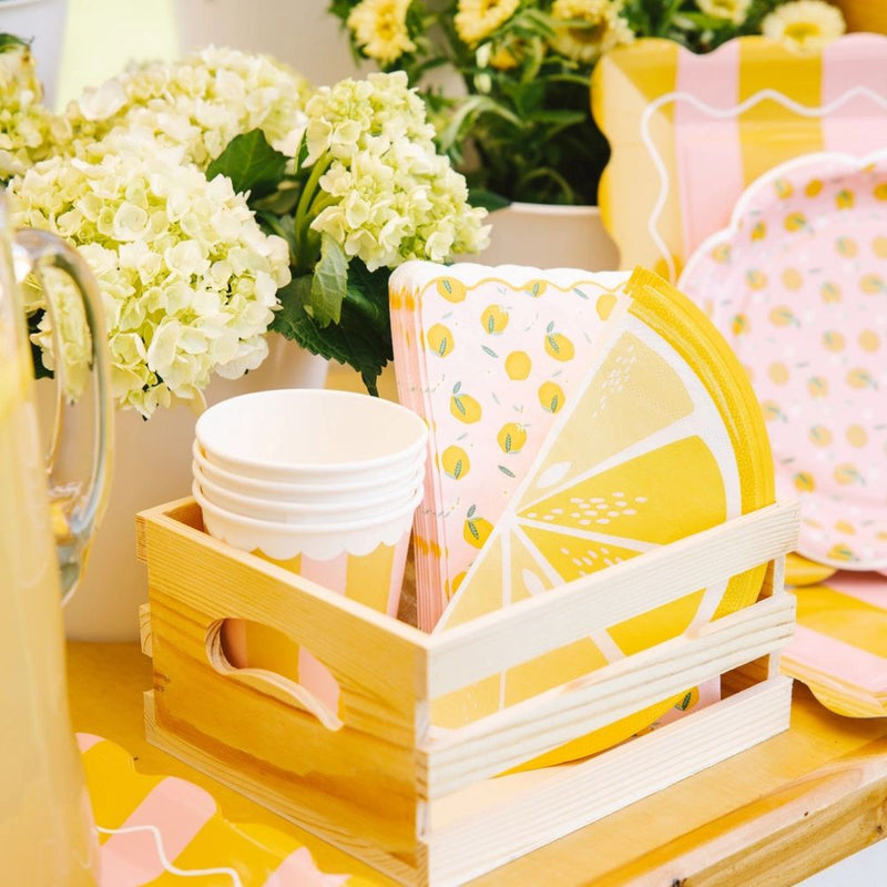 Lemon themed party setup with napkins, cups, and floral decor