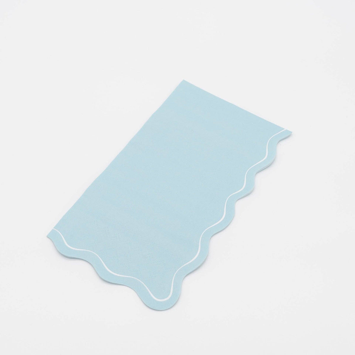 Folded light blue guest towel on a plain surface showing the blue color and wavy scalloped edge.