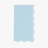 Solid light blue guest towel with a soft wavy scalloped white-outlined edge, flat view on white background.