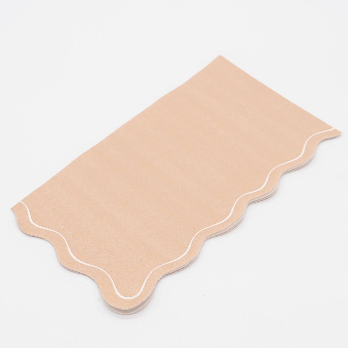 Close-up of the light brown paper guest towel showing the flowing scalloped edge and white outline detail.