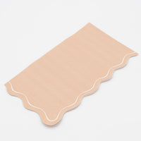 Close-up of the light brown paper guest towel showing the flowing scalloped edge and white outline detail.