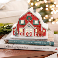 Close-up of the lighted paper barn display, showing the warm glow and realistic glitter texture on the roof.