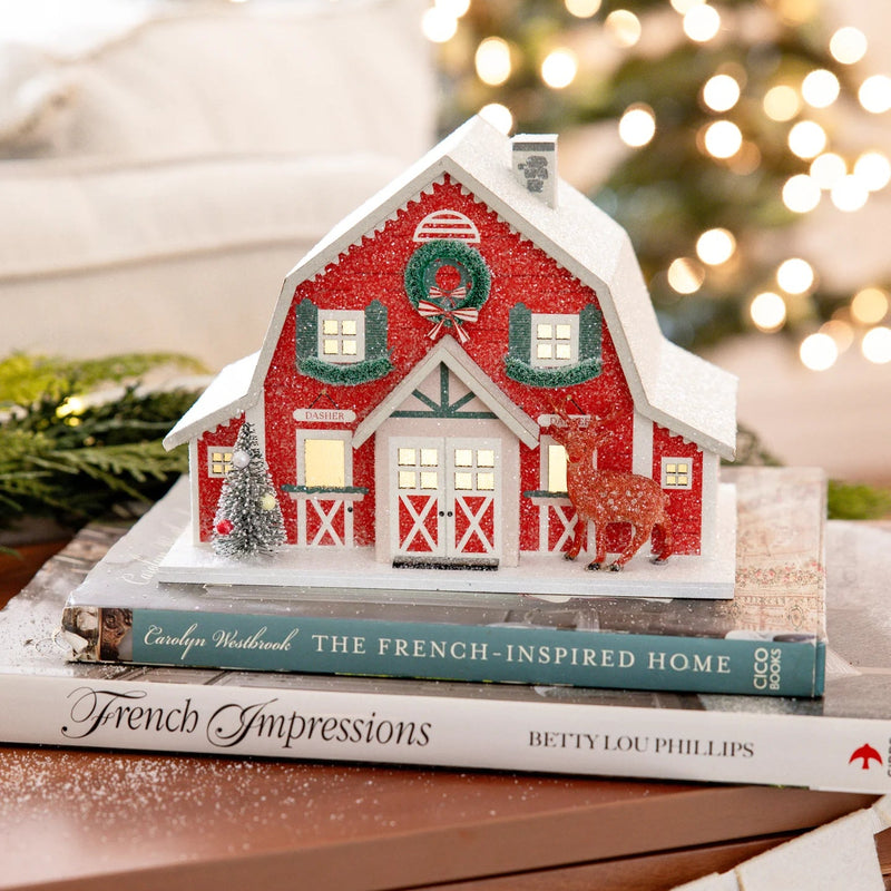 Close-up of the lighted paper barn display, showing the warm glow and realistic glitter texture on the roof.