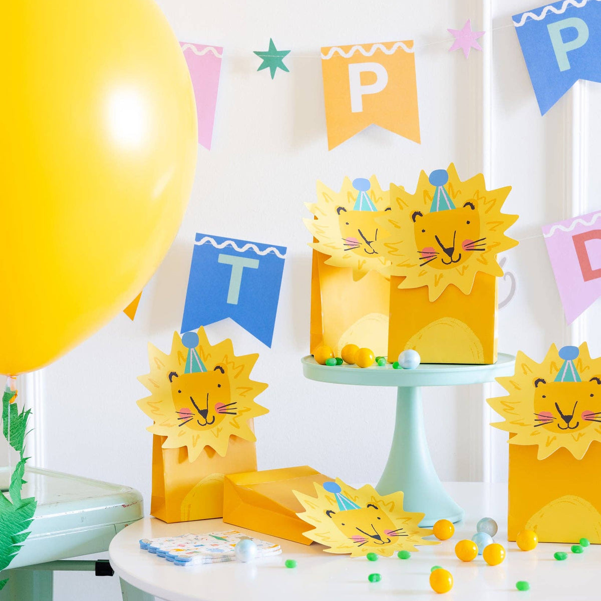 Set of lion themed treat bags arranged on birthday party table with candy decorations