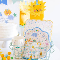 Lion shaped napkins displayed with animal party plates, cups, and decorations for kids birthday party.