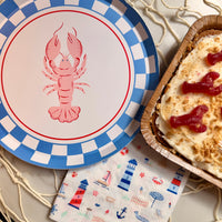 Lobster-themed plate with a checkered border, a dessert in a wooden container, and a nautical-themed napkin.