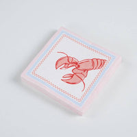 Stack of sixteen folded square paper cocktail napkins on a white surface, slightly elevated angle. Top napkin shows the full lobster illustration centered on white, with blue dotted inner border and pink outer edge. Napkin edges show pink tint from border printing.