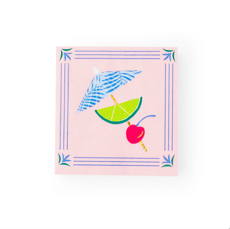 Single folded napkin showing blue drink umbrella, green lime wedge, and red cherry garnish on pale‑pink background.