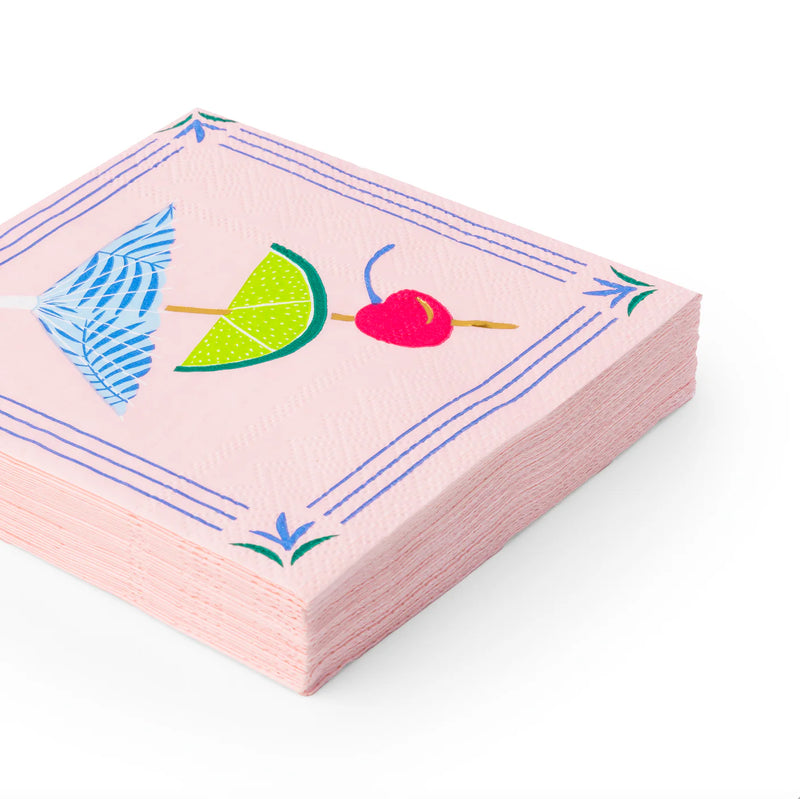 Stack of pink 3‑ply cocktail napkins with umbrella, lime slice, and cherry illustration.