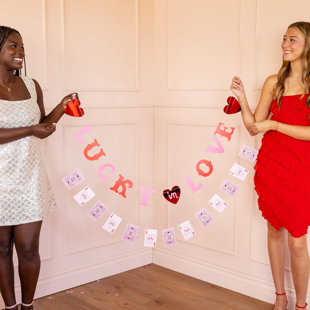 Girls holding Lucky in Love banner featuring heart and playing card details