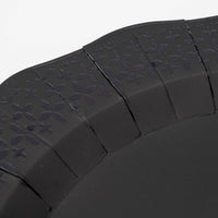 Extreme macro detail highlighting the precision laser-cut cross and floral patterns on the black paper plate border.