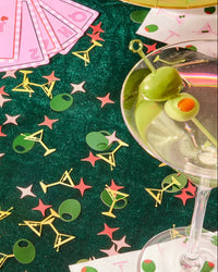 Martini confetti styled on green velvet casino tablescape with real martini glass, playing cards, and paper cocktail napkins