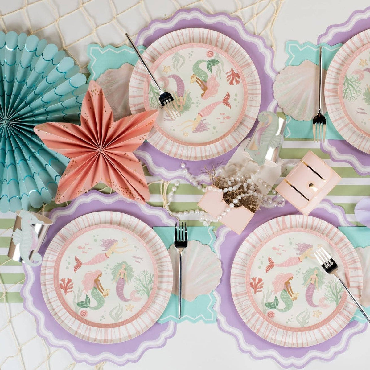 mermaid party table with lavender placemats, shells, and paper fans