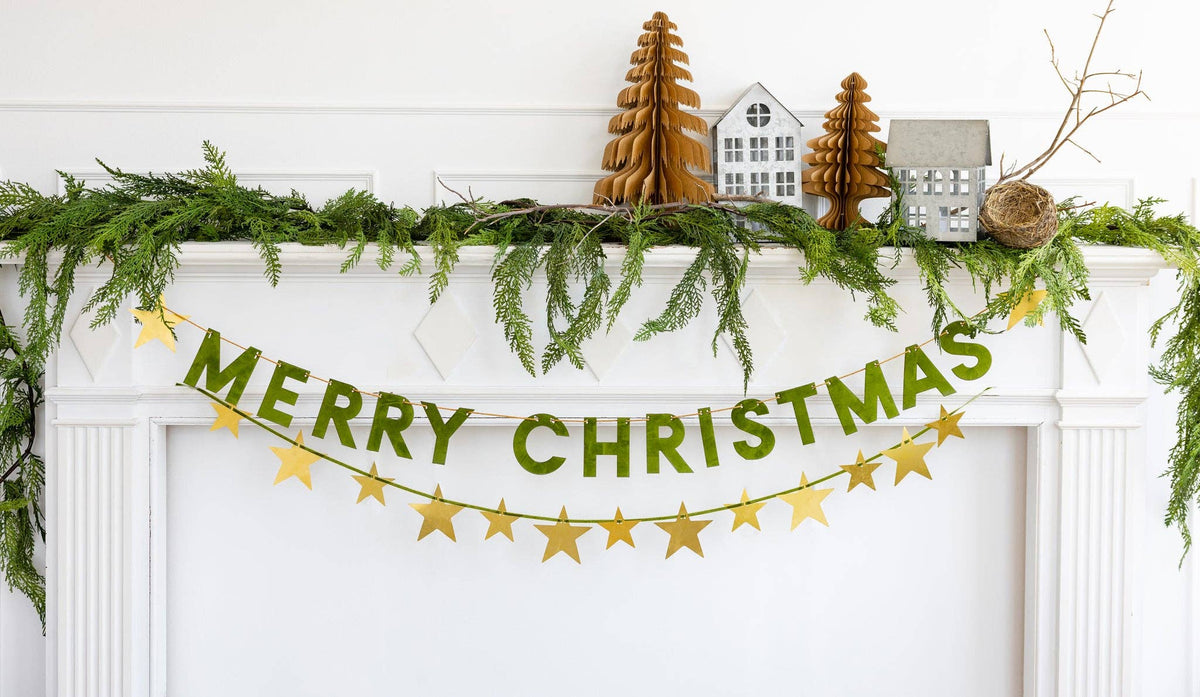Merry Christmas flocked banner hung on a door with garland and mini trees