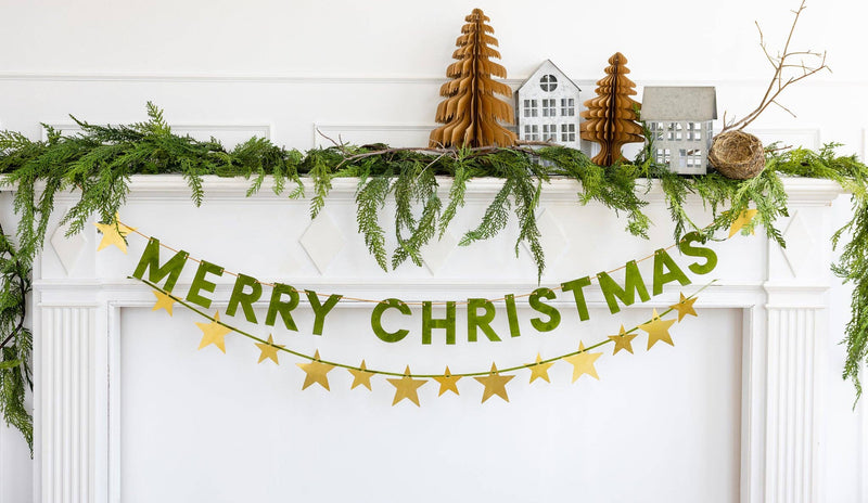 Merry Christmas flocked banner hung on a door with garland and mini trees