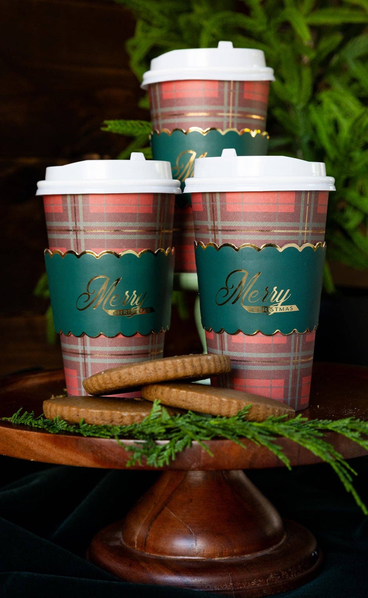 Three Merry Christmas plaid to go cups styled with greenery