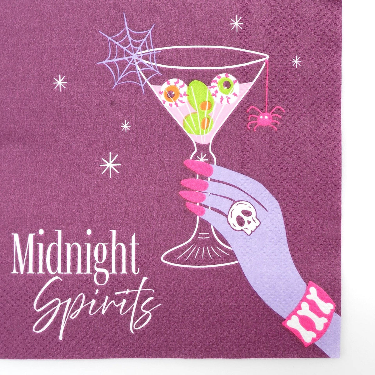 Close-up of the plum Midnight Spirits Halloween cocktail napkin with an eyeball martini, spiderweb, pink spider, and white script text