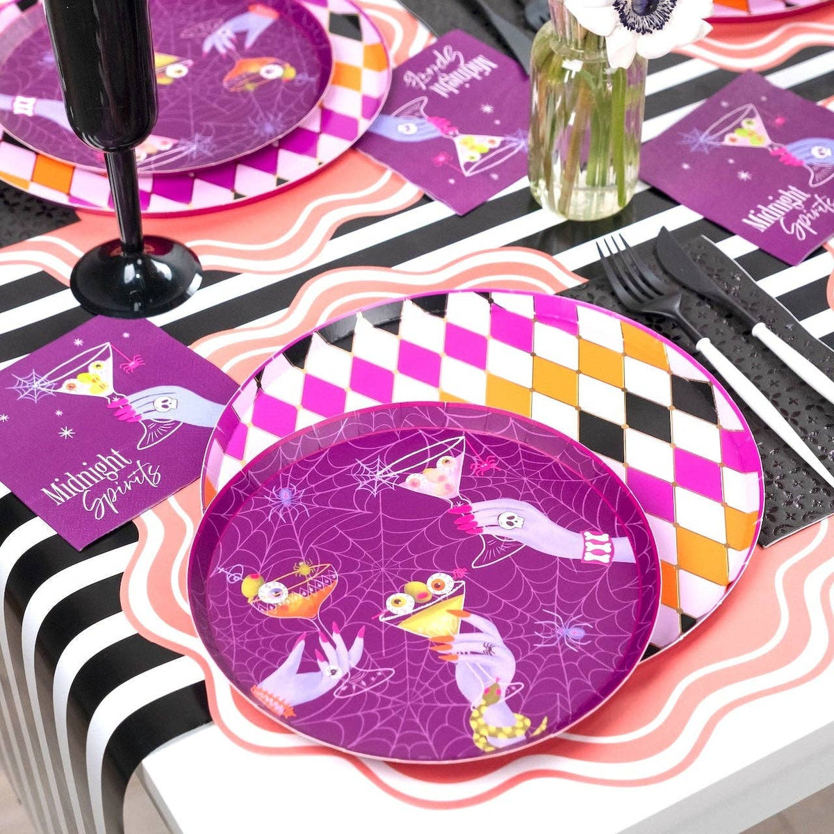Purple Midnight Spirits Halloween plate with the martini cocktail design, pink scalloped charger, purple harlequin pattern, and black cutlery