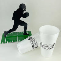 White 20 oz foam cup with 4th DOWN logo beside a black football runner cutout on a green field.