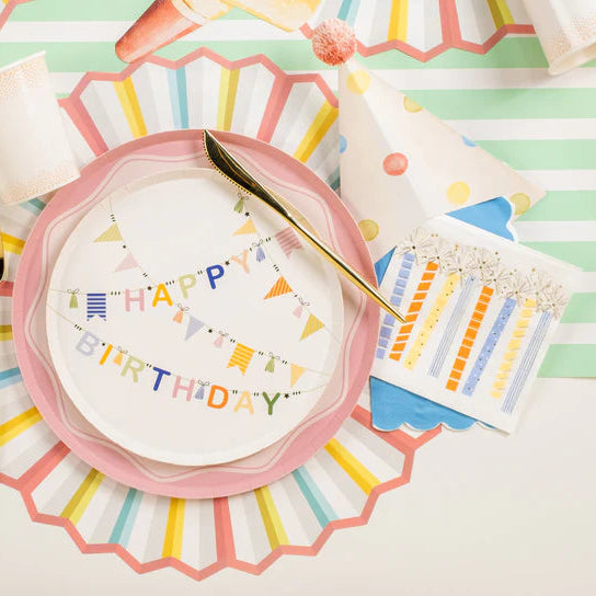 Close place setting with Happy Birthday plate and a candle print beverage napkin to the right.