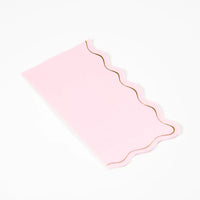 Blush pink guest towel showing scalloped gold edge on white background.