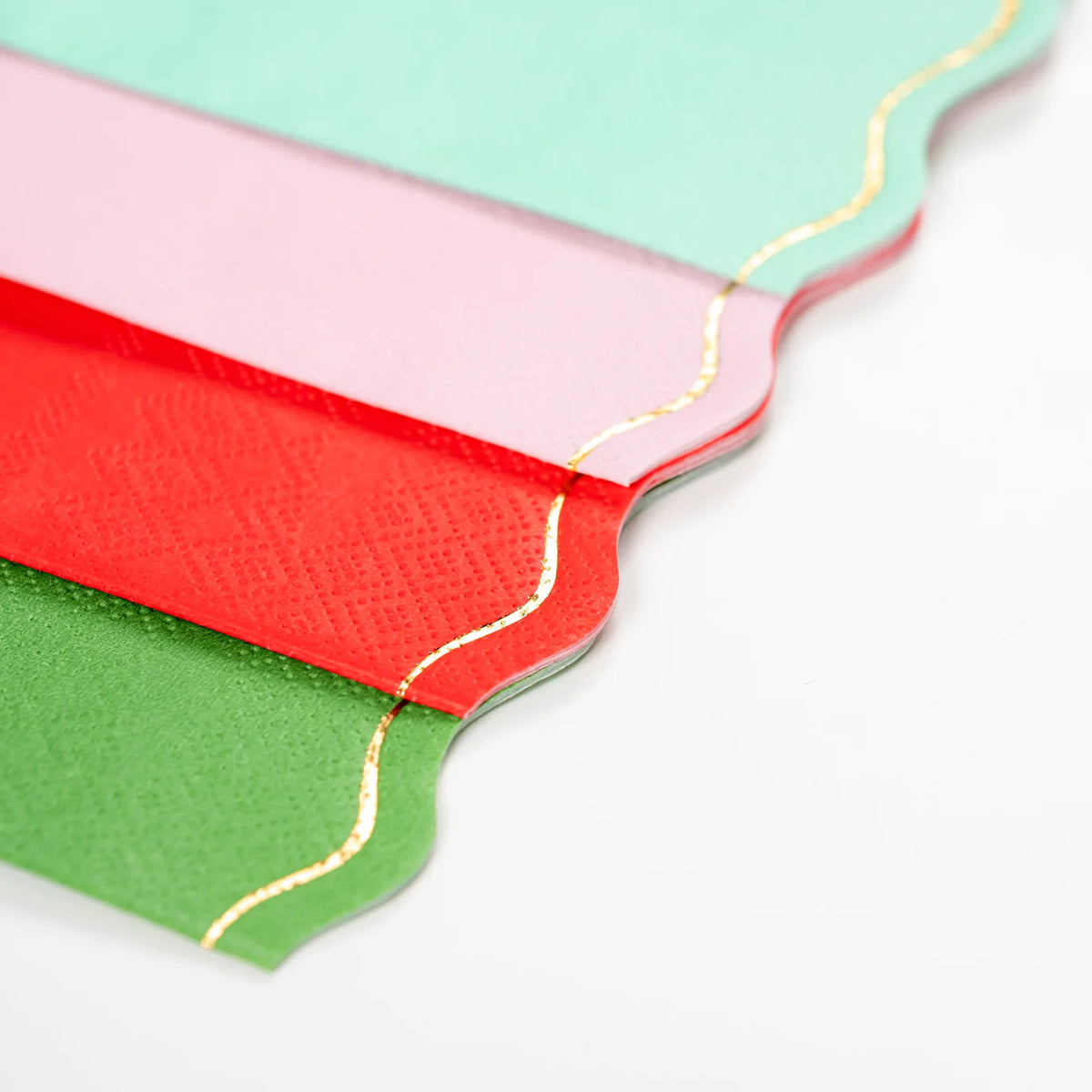 Stack of four guest towels in green, red, pink, and blue with gold edges.