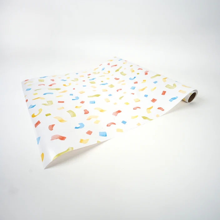 Partially unrolled confetti paper runner lying at an angle on a white surface.