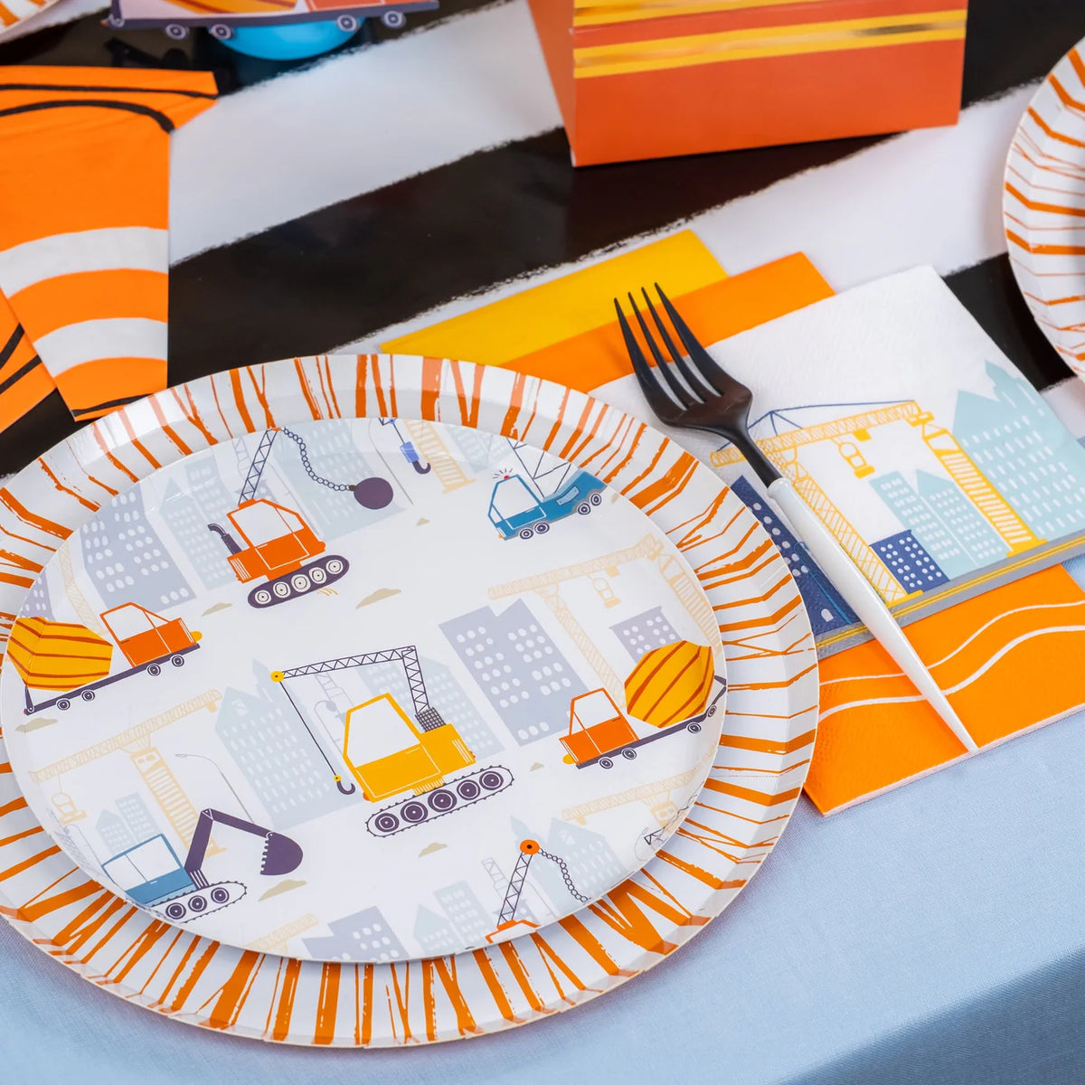 Angle view of construction plate stack with crane napkin and orange decor.