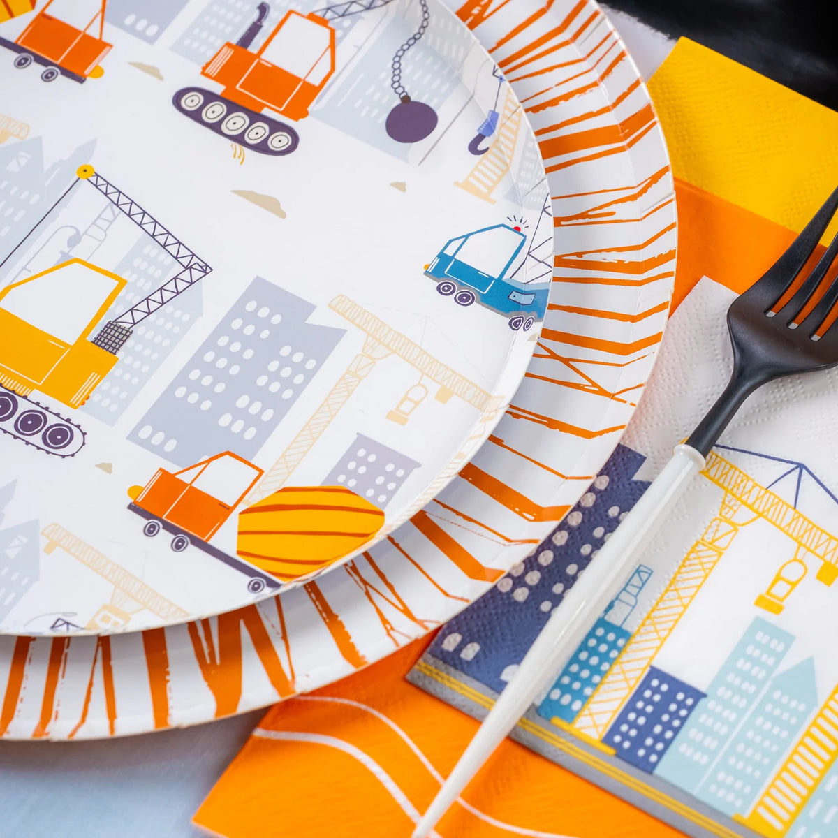 Construction plate stacked on striped charger with fork and crane napkin.
