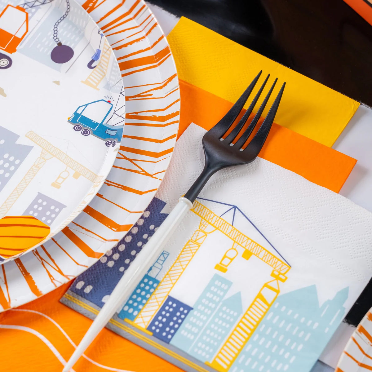 Black fork resting on crane napkin with orange and yellow napkins underneath.