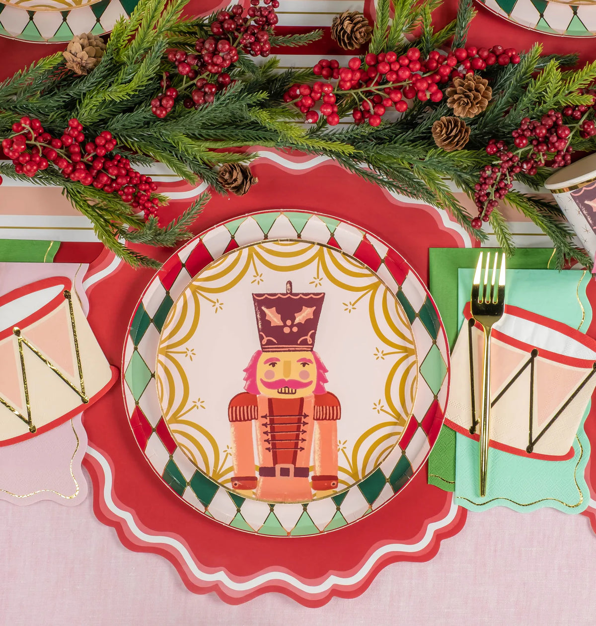 Overhead tablescape with multiple diamond rim plates and holiday greenery down the center.
