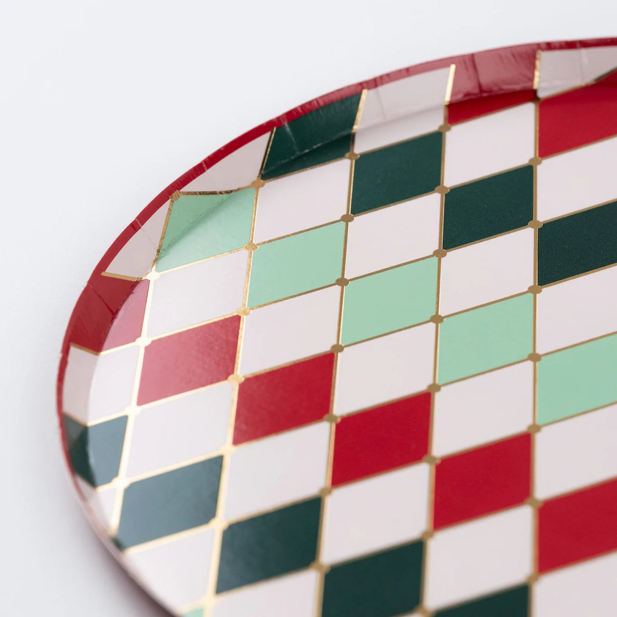 Close detail of red, green, mint, and white diamonds with thin gold lines on the plate rim.