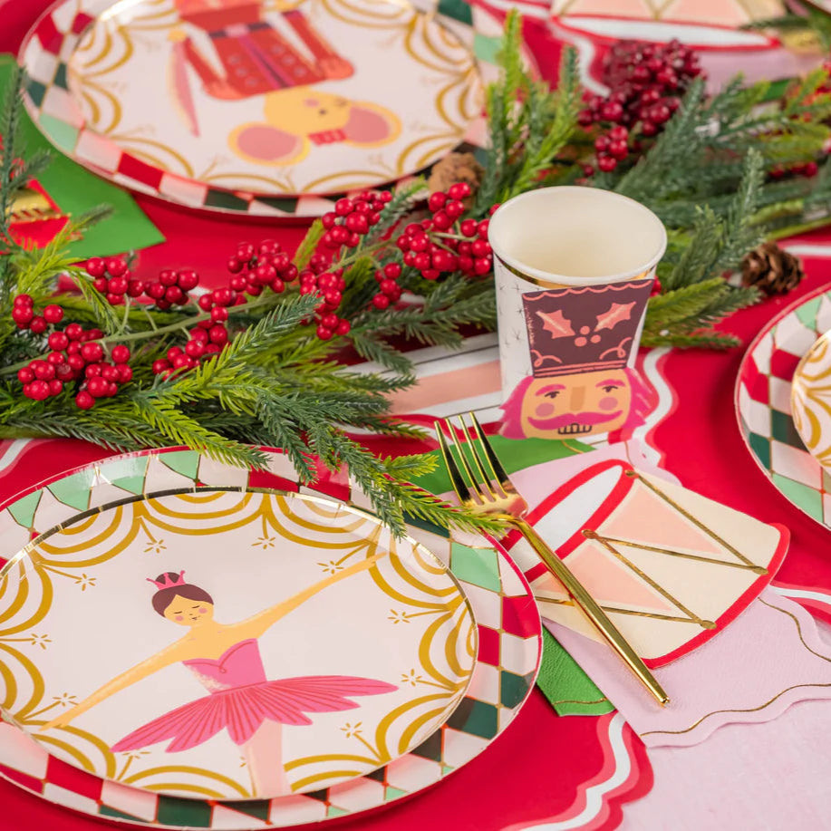 Plates with nutcracker and ballerina designs layered on diamond rims along a red runner.