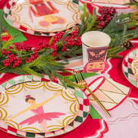 Plates with nutcracker and ballerina designs layered on diamond rims along a red runner.