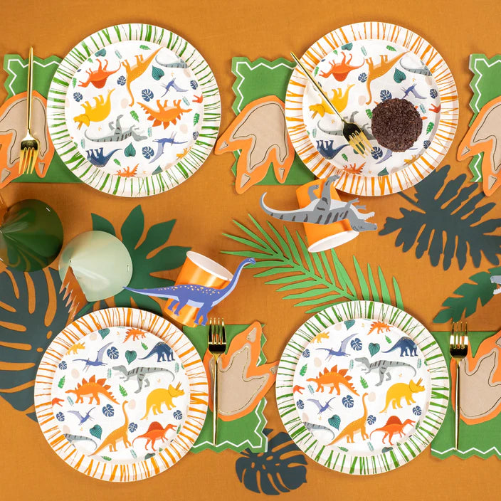 Overhead table spread with multiple dinosaur plates and footprint napkins.
