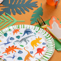 Detail of plate rim and gold fork beside green leaf decorations.
