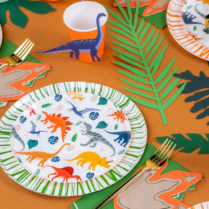 Dinosaur dessert plate at a styled table with orange cup and green leaves.