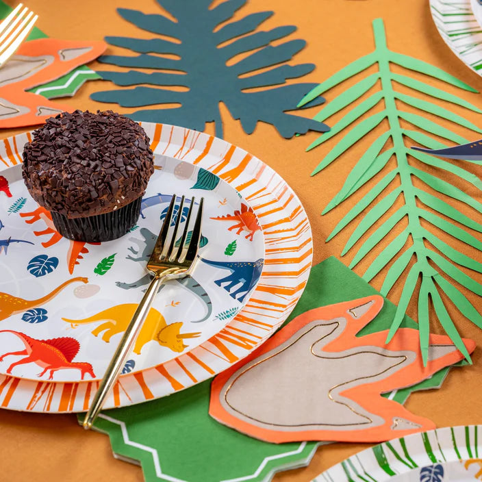 Cupcake on stacked plates with green leaf runner and dino footprint napkin.