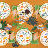 Angled table view showing dino plates, orange cups, and stickers as accents.