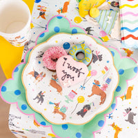 Overhead place setting with dog party plate on a mint scalloped charger and frosted dog treats.