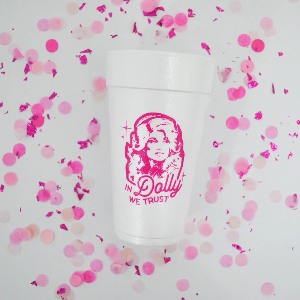 Overhead view of “In Dolly we trust” foam cup scattered with pink confetti pieces.