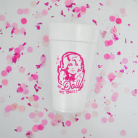 Overhead view of “In Dolly we trust” foam cup scattered with pink confetti pieces.