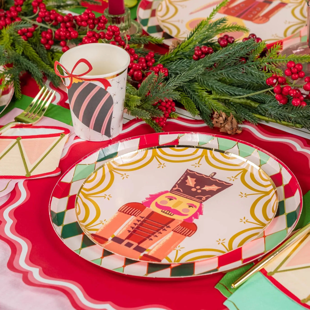 Close place setting showing nutcracker plate beside pink candle and ornament cup with drum napkin.