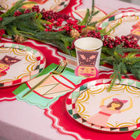 Side angle of table featuring Clara plate, greenery, and a drum napkin next to gold flatware.