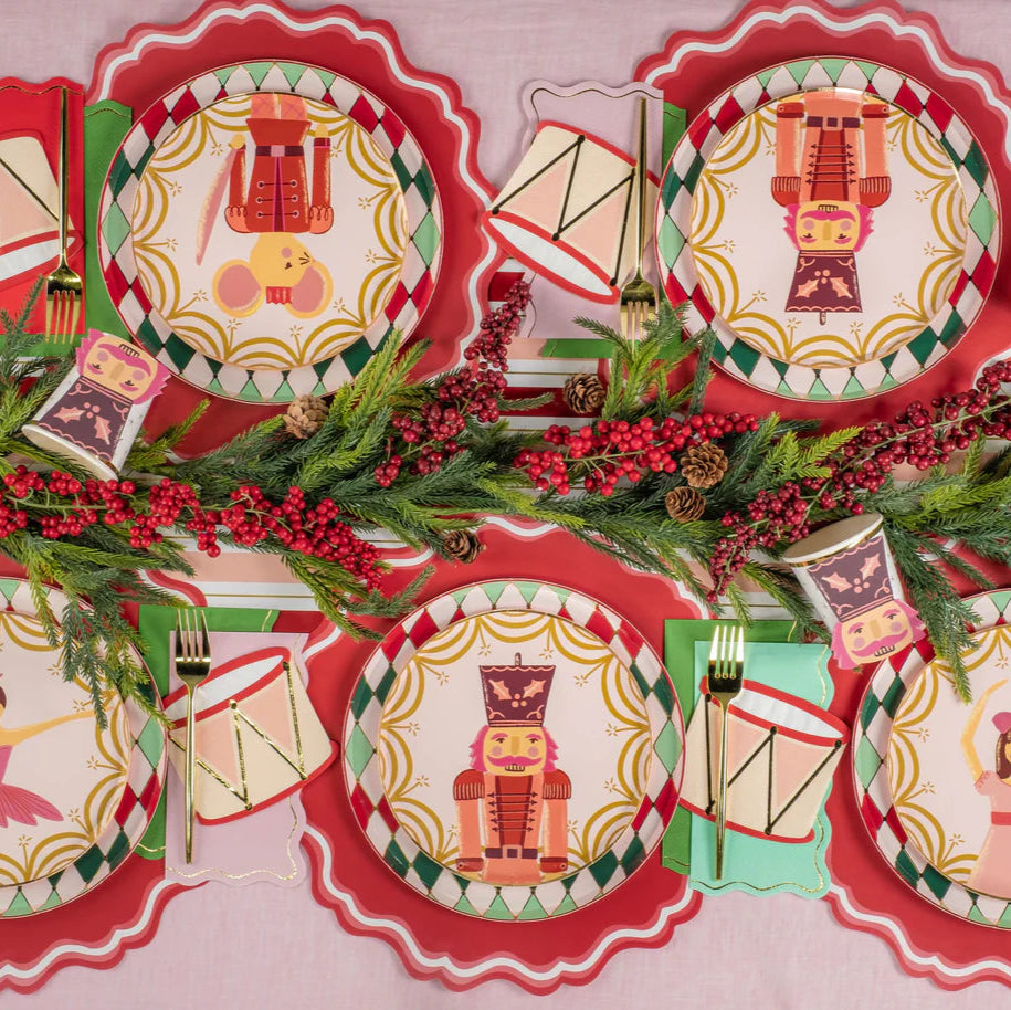 Overhead tablescape with multiple character plates and drum napkins layered on red placemats.